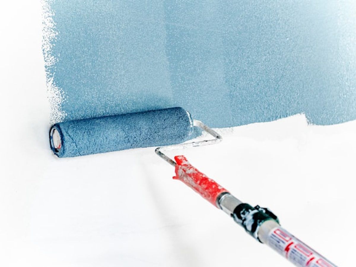 Painter rolling paint onto a wall